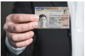 A hand holding a Spanish "Permiso de Residencia" (TIE) card for study and research purposes.