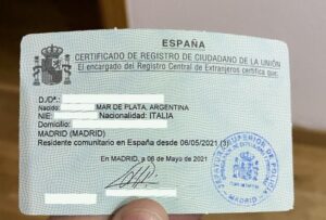A close-up of a person holding the official "Certificado de Registro de Ciudadano de la Unión," a small green document used for EU residency in Spain.