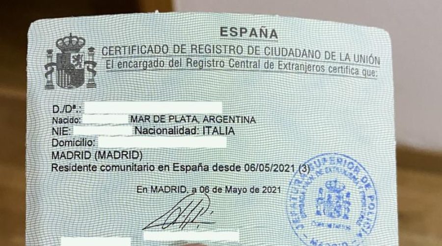 A close-up of a person holding the official "Certificado de Registro de Ciudadano de la Unión," a small green document used for EU residency in Spain.
