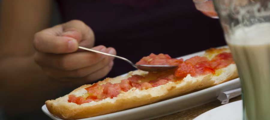 Four slices of toasted rustic bread topped with fresh grated tomato and salt, served on a wooden board.